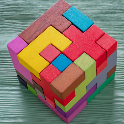 A colourful cube made from wooden pieces of different shapes.