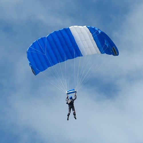 A person skydiving with a blue and white parachute.