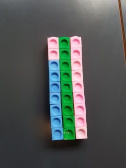 a tower of 7 blue and 2 pink cubes next to a tower of 9 green cubes and a tower of 9 pink cubes