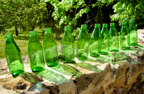 Ten green glass bottles on a wall.