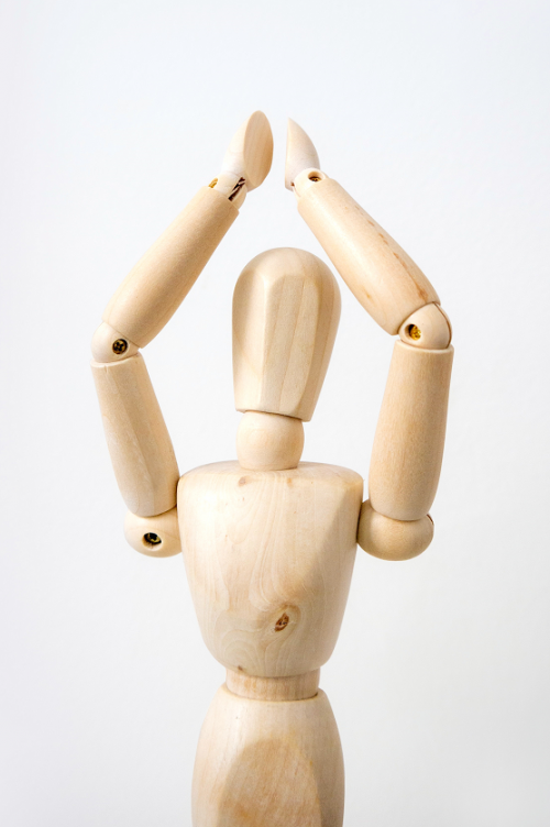 Wooden mannequin clapping above its head.