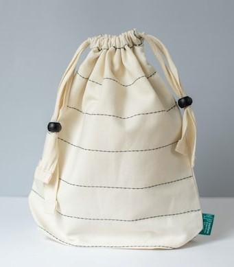 Shapes in the Bag A cream drawstring bag with thin black stripes, perhaps containing different shapes inside it.