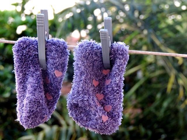 A pair of purple fluffy slipper socks hanging outside on a washing line.
