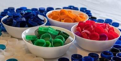 Counting Collections Four white bowls containing bottle caps sorted by colour. The caps are red, green, yellow and blue.