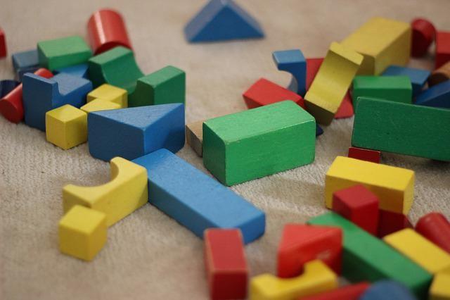Building Towers Coloured wooden blocks of different shapes and sizes are scattered over a carpet.