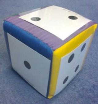 Dice A large die used as a soft toy, placed on a blue carpet.. The faces with one, two and four pips are visible.