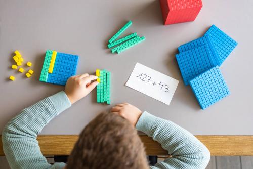 Overhead photo of buy playing with blue and teal lego bricks on a table