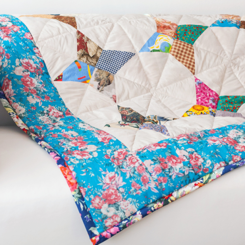 A blue patchwork quilt draped over a white sofa.