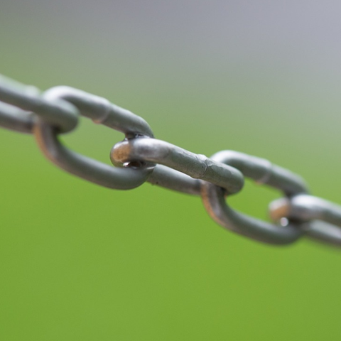 A silver metal chain with a green background.
