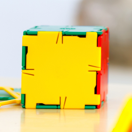 A colourful cube made from a plastic Polydron net.