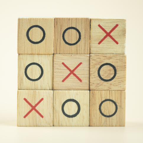 A wooden noughts and crosses game, with three crosses in a diagonal row.