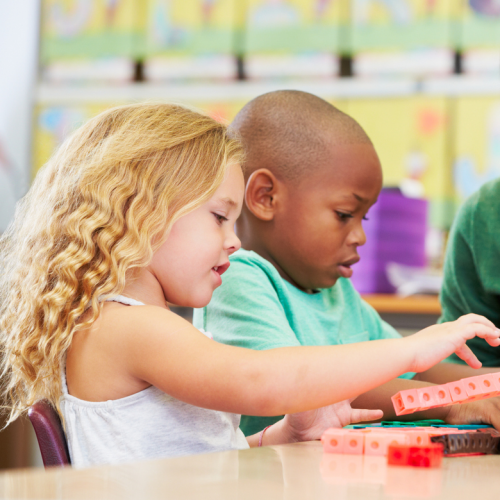 A boy and a girl looking at linking cubes.