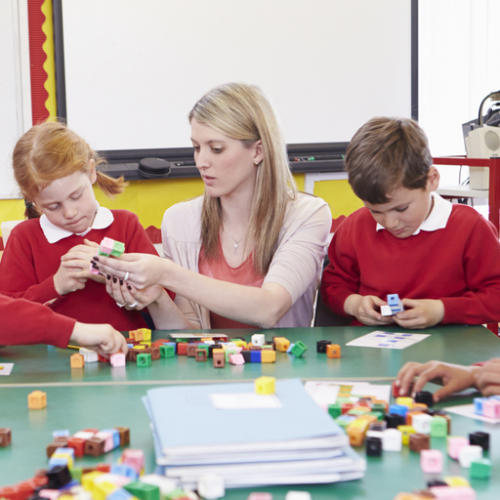 Two children and a teacher using multilink cubes.