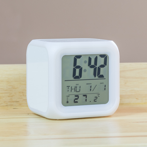 A digital alarm clock on a wooden table.