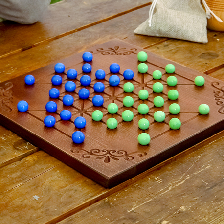 The board game Alquerque, with green and blue balls on a game board.