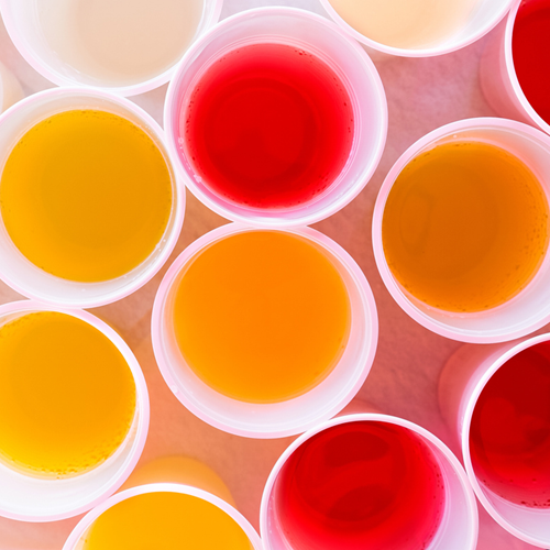 A selection of diluted squash drinks in white plastic cups.