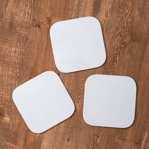 Three blank drinks coasters on a wooden table.