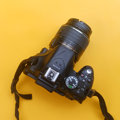 A professional digital camera on a yellow background.