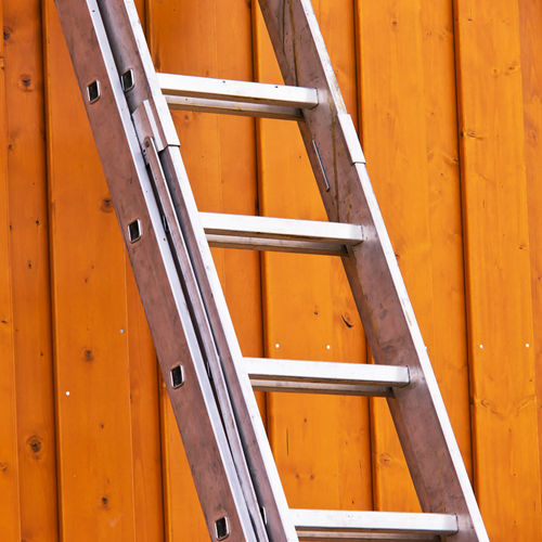 A metal ladder leaning against a wooden wall.