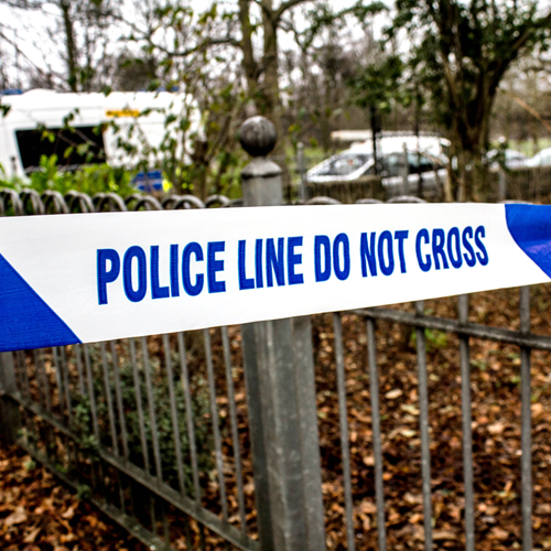 A park with police tape across the fence.