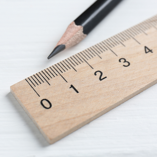 A wooden ruler showing centimetres, with a pencil beside it.