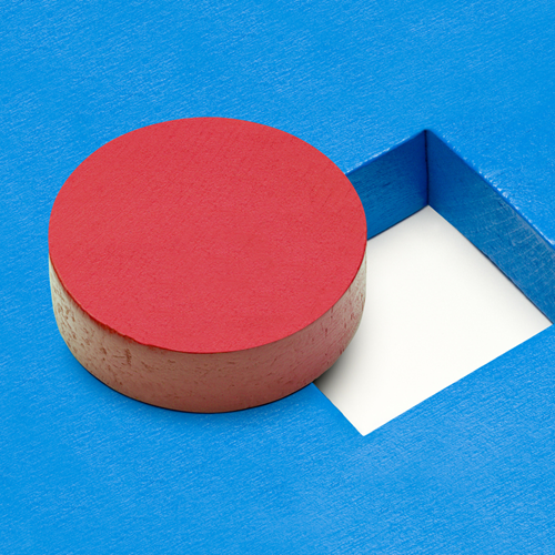 A round wooden block beside a square hole.