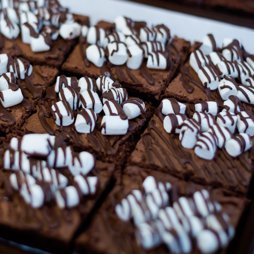 A tray back of brownies with marshmallows on top.