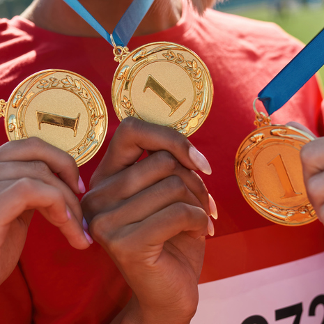 Three athletes holding first place medals.