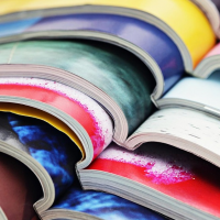 A stack of open magazines on colourful pages.