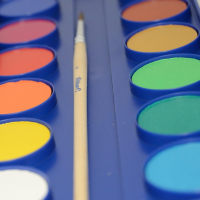 Paintbrush and different coloured watercolour paint blocks.