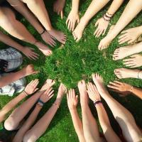 Lots of people's hands and arms all reaching out towards a central point.