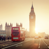 Westminster Bridge at sunset with pedestrians and a red bus.