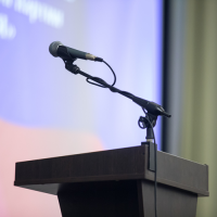 A microphone on a podium with a slideshow on a screen behind it.