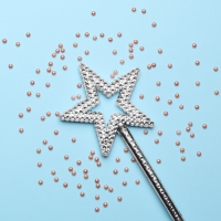 A silver magic wand and confetti on a blue background.