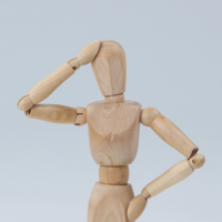 A wooden mannequin with its hand on its head in a thinking pose.
