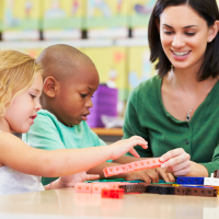 Two children and their teacher looking at sticks of linking cubes.